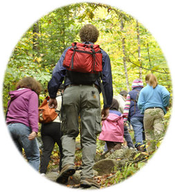 Hikers with children in early autumn; foloiage a yellow-green.