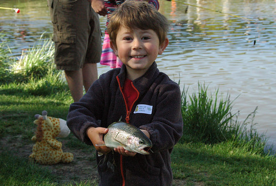 smiling boy holds fish in hand