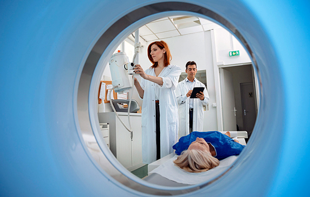 Two radiology technicians preparing to perform a CT scan on a patient.