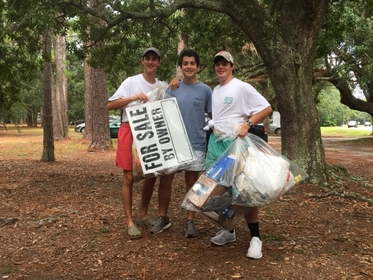 Three people pose with their trash at the International Coastal Cleanup.