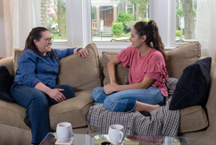 Image shows two women sitting on a couch and talking 