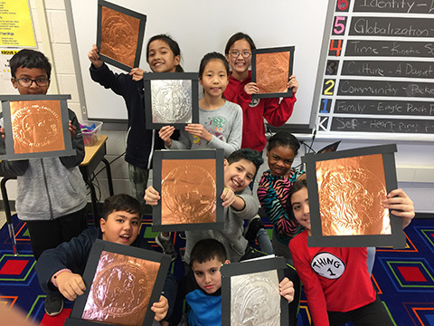 Students holding up artwork.