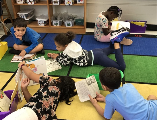 Photo of several students reading on the carpet